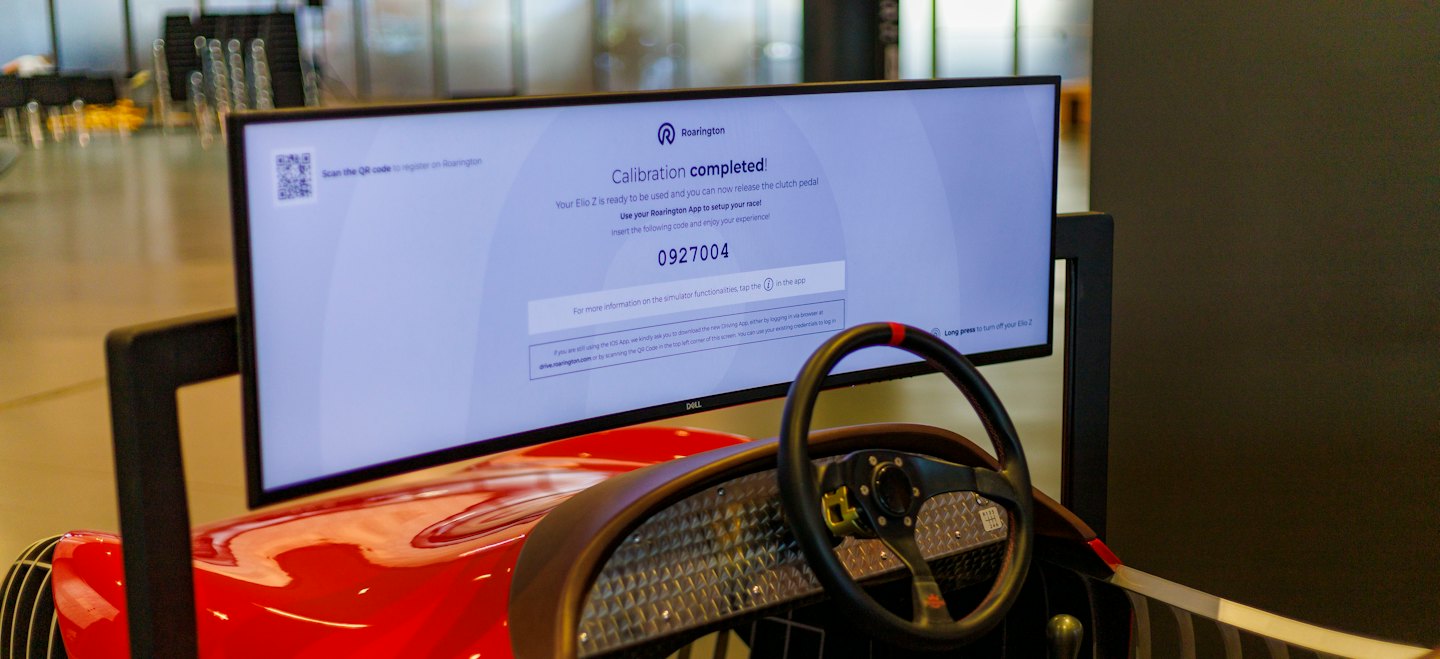 Un display rosso di un simulatore di corse che mostra istruzioni di configurazione e codici di registrazione.
